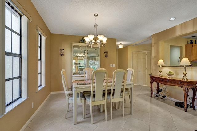 dining area with light tile patterned flooring, plenty of natural light, a textured ceiling, and an inviting chandelier