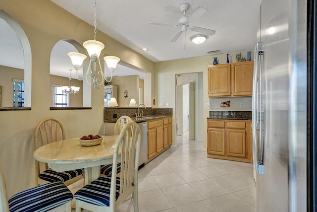 kitchen featuring ceiling fan with notable chandelier, a sink, freestanding refrigerator, arched walkways, and light tile patterned floors