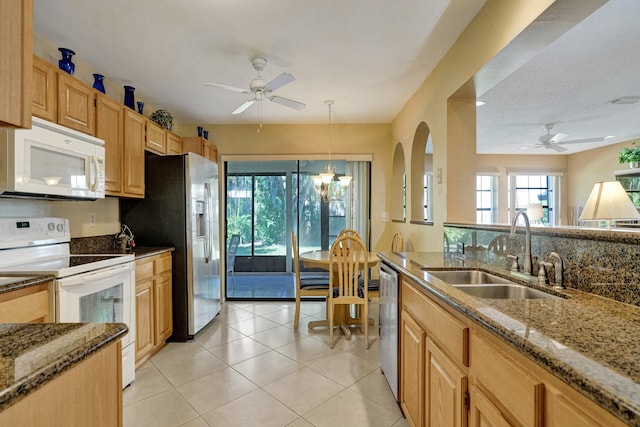 kitchen featuring a sink, dark stone countertops, a ceiling fan, and stainless steel appliances