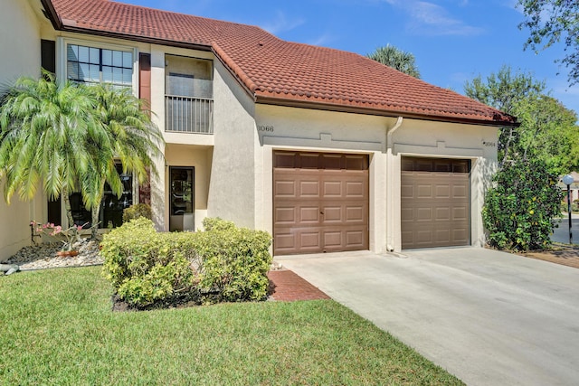 mediterranean / spanish-style house with stucco siding, a front lawn, driveway, a tile roof, and a garage