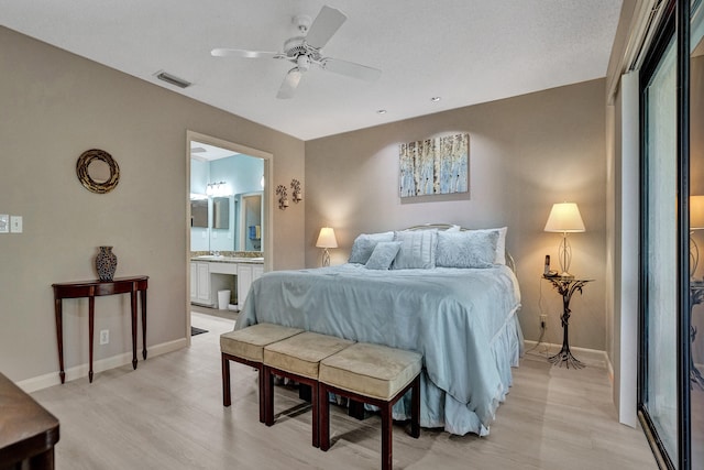 bedroom featuring visible vents, baseboards, connected bathroom, and light wood finished floors