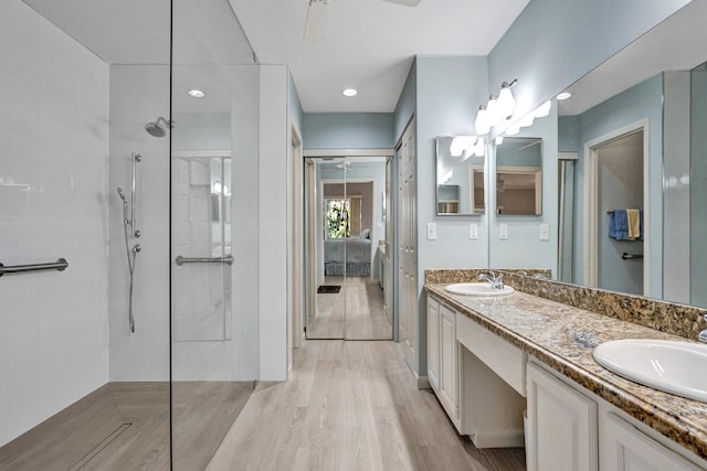 bathroom with wood finished floors, a walk in shower, double vanity, and a sink