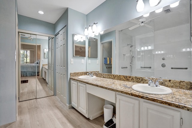 bathroom with a sink, wood finished floors, a tile shower, and ceiling fan