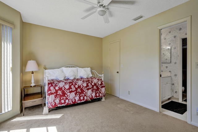 bedroom with baseboards, visible vents, ensuite bathroom, a textured ceiling, and carpet flooring