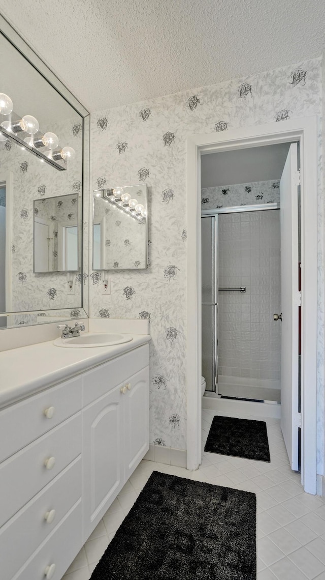 bathroom with wallpapered walls, tile patterned flooring, and a textured ceiling