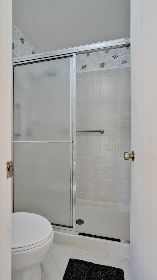 full bathroom featuring toilet, a shower stall, and tile patterned flooring