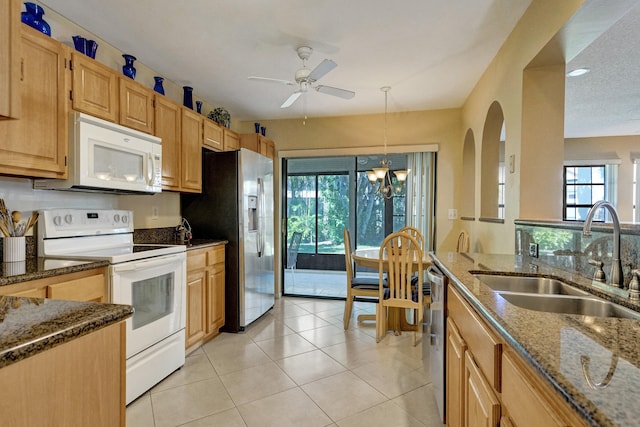 kitchen featuring ceiling fan, dark stone countertops, appliances with stainless steel finishes, light tile patterned flooring, and a sink