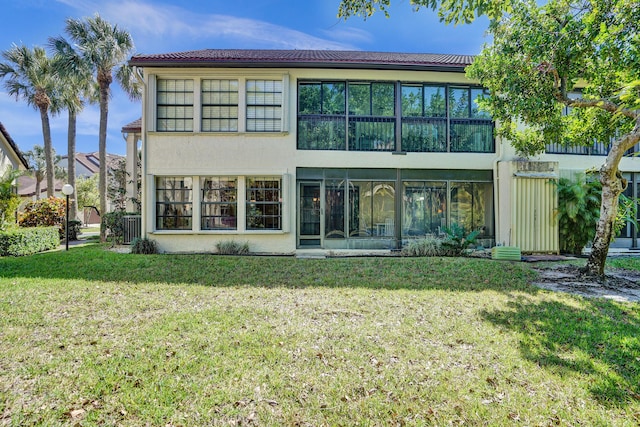 back of house featuring stucco siding, a tile roof, and a yard