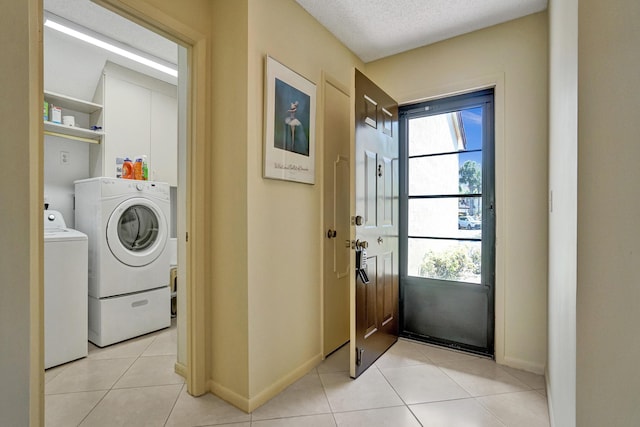 washroom with baseboards, laundry area, light tile patterned flooring, washer and dryer, and a textured ceiling