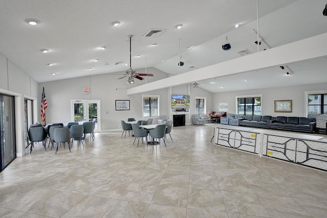 interior space with visible vents, a ceiling fan, open floor plan, and high vaulted ceiling