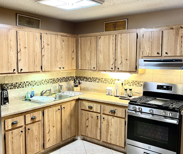 kitchen with light tile patterned floors, light countertops, stainless steel gas range oven, exhaust hood, and backsplash