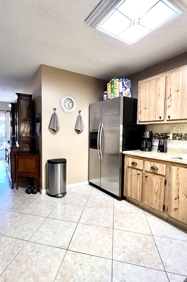 kitchen with light tile patterned floors, decorative backsplash, light countertops, and stainless steel fridge with ice dispenser