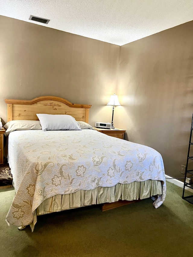 bedroom with visible vents, a textured ceiling, and carpet floors