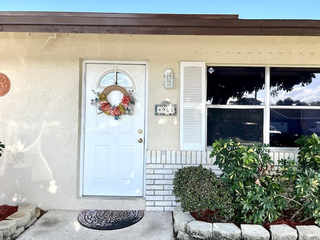 view of exterior entry featuring stone siding and stucco siding