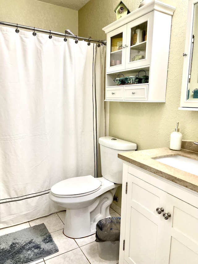 bathroom featuring vanity, curtained shower, tile patterned floors, toilet, and a textured wall