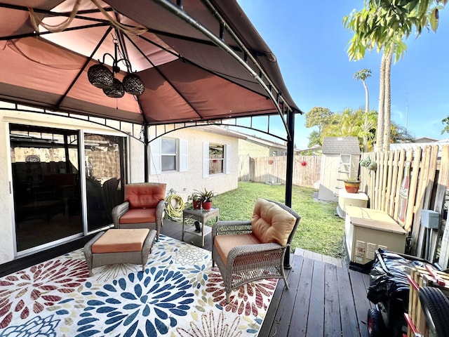 deck featuring a fenced backyard, a gazebo, an outdoor structure, a storage unit, and a lawn