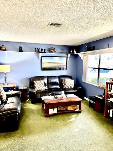 carpeted living area with visible vents and a textured ceiling