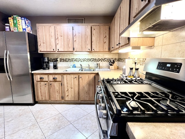 kitchen with light tile patterned floors, a sink, stainless steel appliances, light countertops, and under cabinet range hood