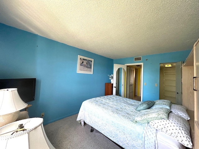 bedroom with baseboards, carpet flooring, a textured ceiling, and visible vents