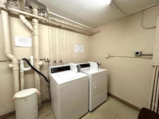 laundry room featuring washer and clothes dryer, a textured ceiling, and baseboards