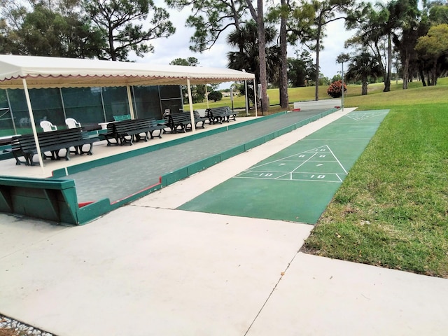 view of community featuring shuffleboard and a yard