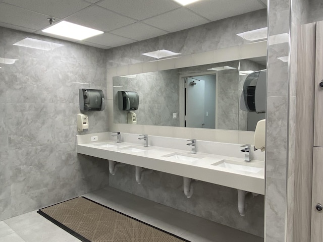 bathroom with a sink, a drop ceiling, and tile walls