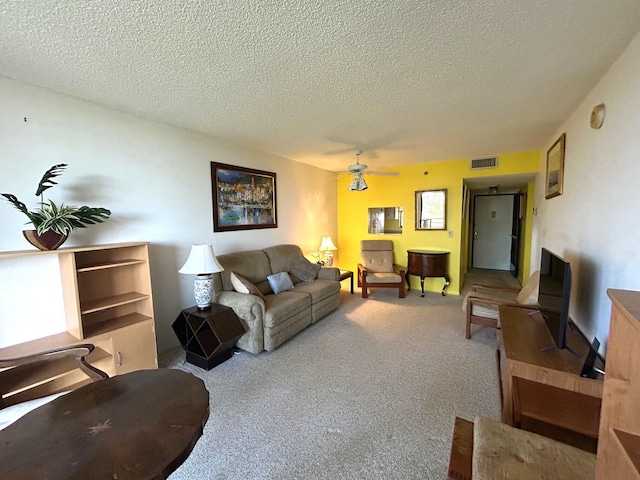 living area with visible vents, ceiling fan, a textured ceiling, and carpet