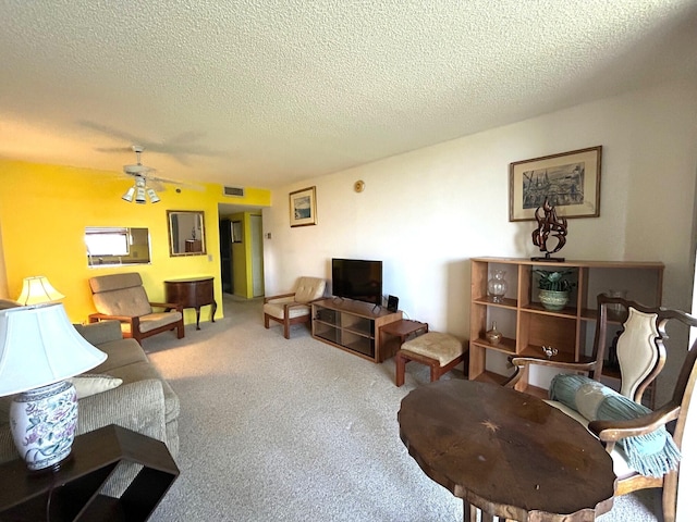 living area with a textured ceiling, carpet, visible vents, and ceiling fan