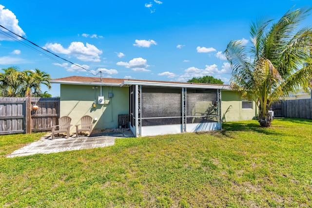 back of property with stucco siding, a lawn, a patio, a fenced backyard, and a sunroom