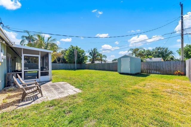 view of yard featuring an outdoor structure, a fenced backyard, a shed, and a sunroom