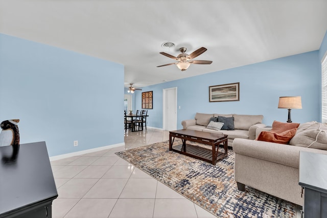 living area featuring light tile patterned floors, visible vents, baseboards, and a ceiling fan