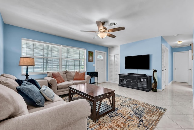 living room with light tile patterned floors, visible vents, baseboards, and a ceiling fan