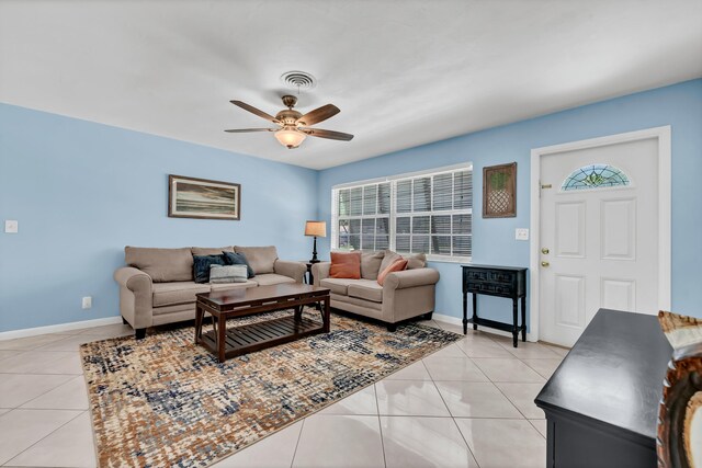 living area featuring light tile patterned flooring, visible vents, baseboards, and ceiling fan