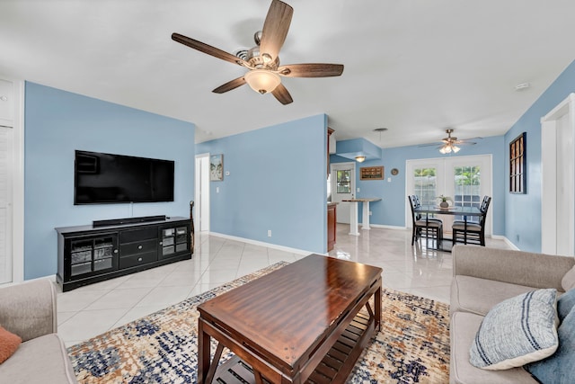 living room featuring light tile patterned floors, baseboards, and a ceiling fan