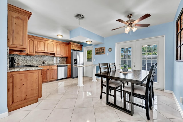 kitchen featuring visible vents, light tile patterned flooring, a sink, stainless steel appliances, and tasteful backsplash