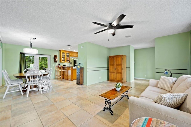 living room featuring light tile patterned floors, a textured ceiling, and a ceiling fan