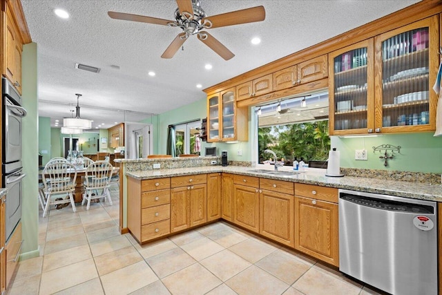 kitchen with light stone countertops, visible vents, a peninsula, a sink, and stainless steel dishwasher