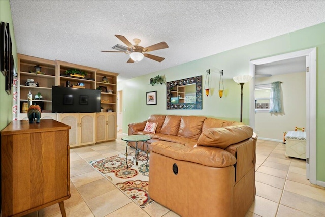 living area featuring light tile patterned floors, baseboards, a textured ceiling, and a ceiling fan