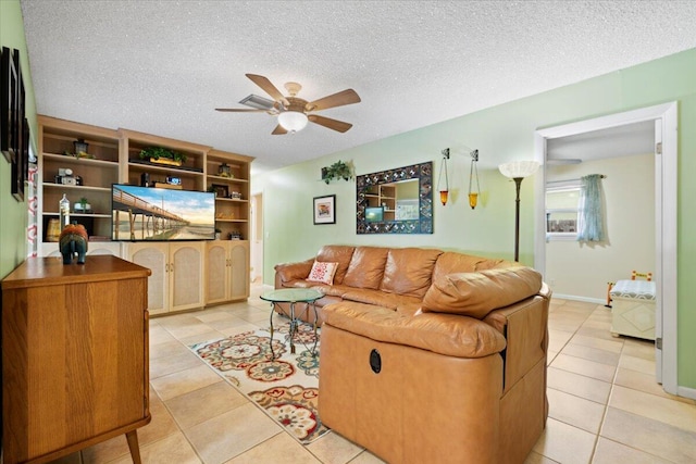 living room with light tile patterned flooring, a ceiling fan, and a textured ceiling