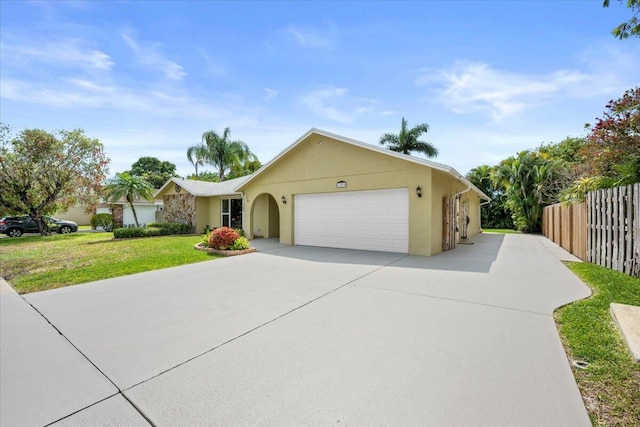 ranch-style home featuring stucco siding, fence, concrete driveway, an attached garage, and a front yard