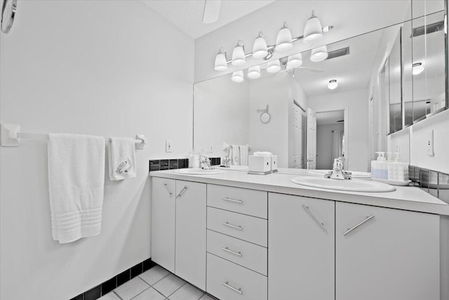 bathroom with tile patterned flooring, double vanity, a textured ceiling, and a sink