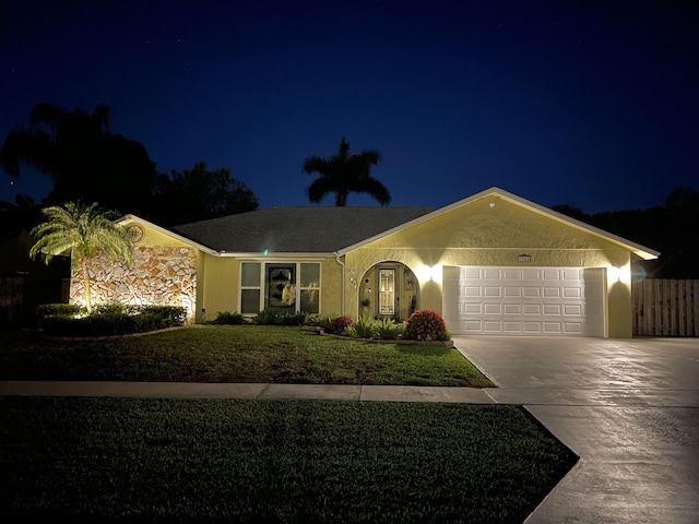 single story home with stucco siding, an attached garage, a yard, and driveway