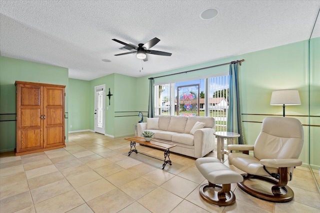 living room featuring light tile patterned flooring, baseboards, a textured ceiling, and a ceiling fan