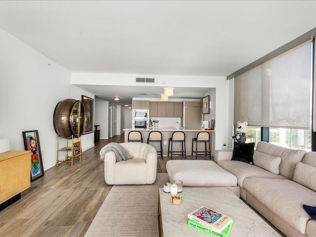 living room with visible vents, baseboards, and wood finished floors