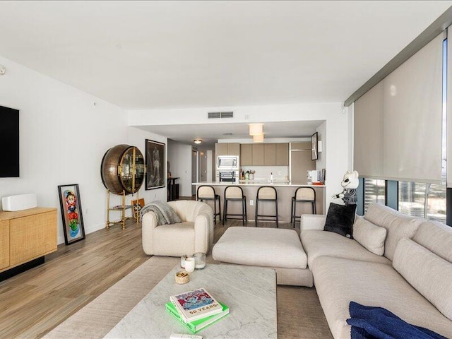 living area with visible vents, baseboards, and light wood-style flooring