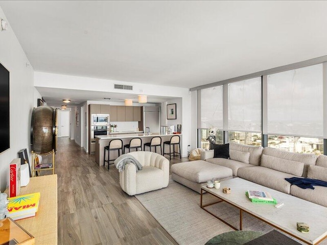 living room with visible vents, wood finished floors, and floor to ceiling windows