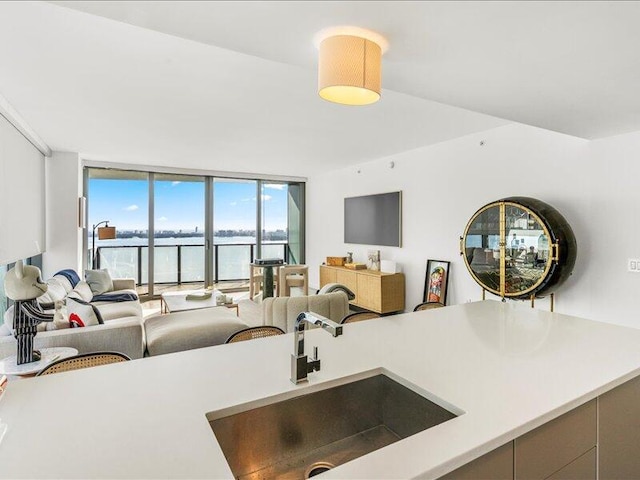 kitchen with light countertops, floor to ceiling windows, open floor plan, and a sink