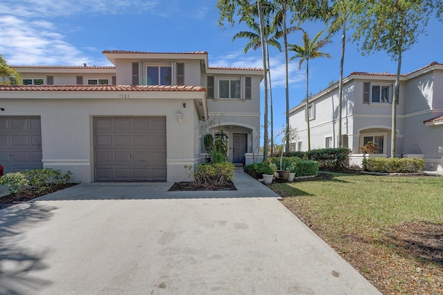 mediterranean / spanish-style house with stucco siding, driveway, a tile roof, and a front lawn