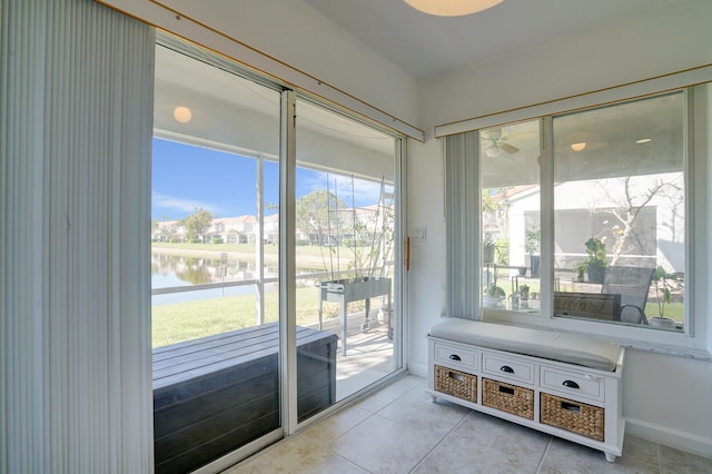 interior space featuring light tile patterned floors, baseboards, a water view, and ceiling fan