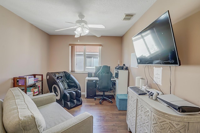 home office featuring visible vents, a textured ceiling, wood finished floors, and a ceiling fan